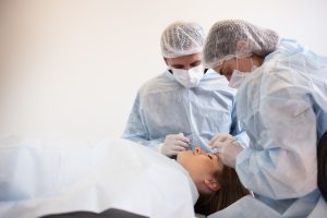 Team of surgeon in uniform perform operation on a patient at plastic surgery clinic