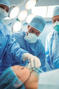 Team of surgeons and anesthesia providers adjusting oxygen mask on patient mouth in operation theater at hospital